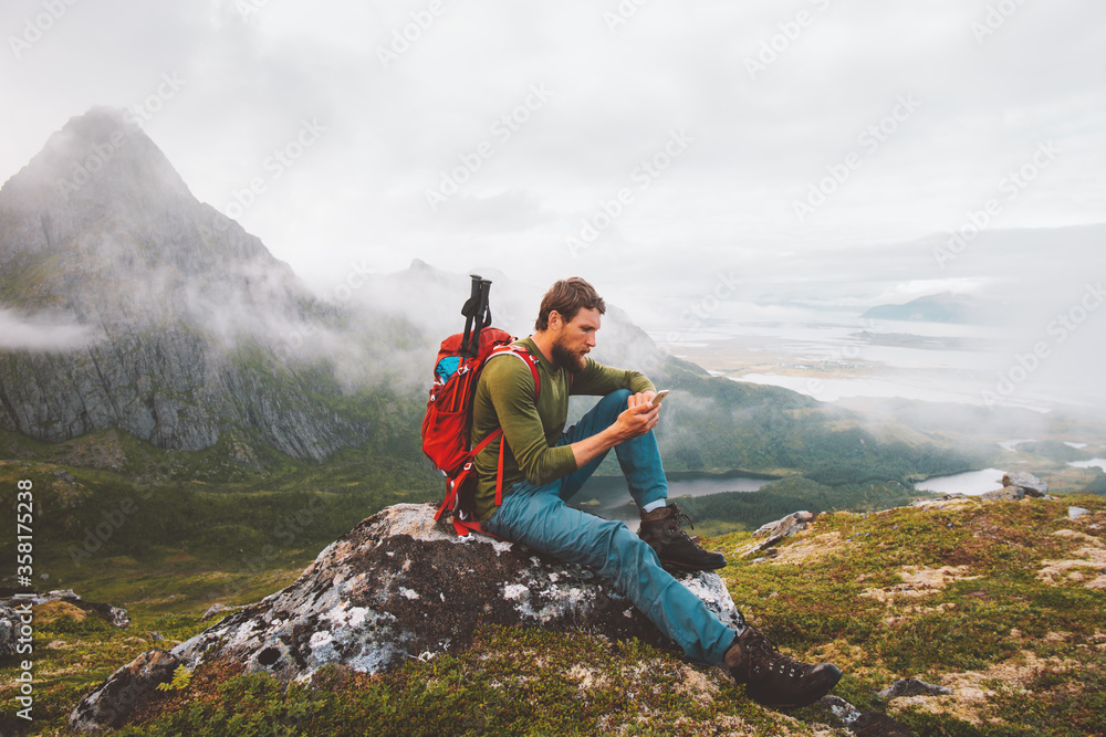 Fototapeta premium Man using smartphone hike in mountains travel blogger influencer lifestyle adventure vacations summer tour outdoor in Norway