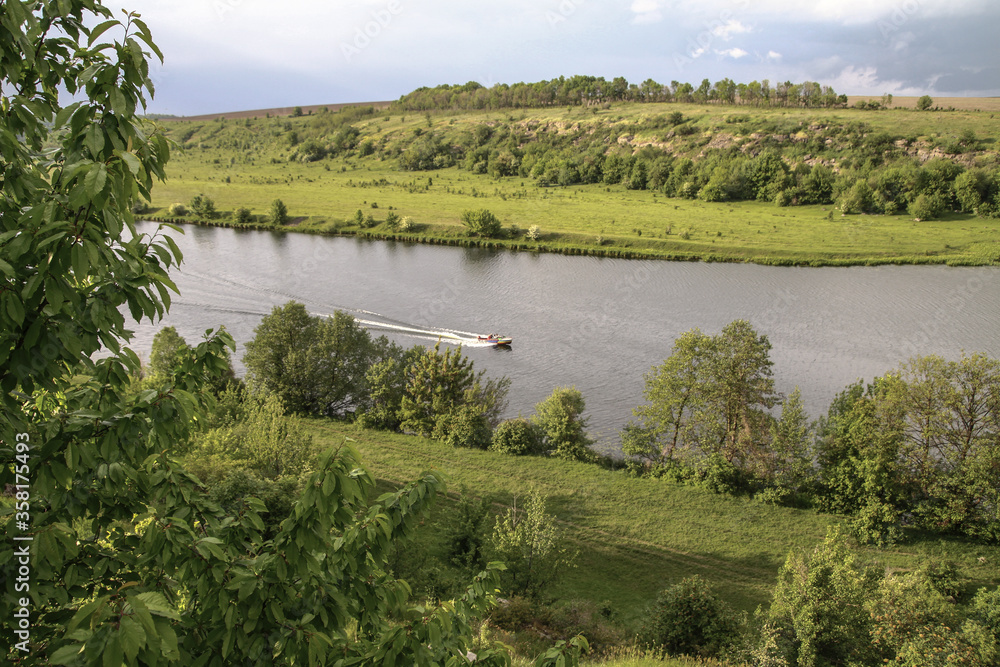Top view of the river with a fast-moving motorboat with tourists in a nature reserve. Fishermen sail on the ship for the catch. Beautiful pretty landscape. Stock photo
