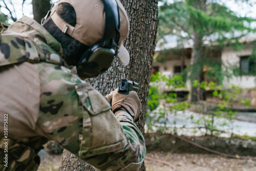 Soldier pointing his gun. USP gun. Airsoft player. Multicam camouflage. Mlitar in the woods. United States Navy. Airsoft guns. United States Navy. Soldier. Marine. Cutting weapon range. Airsoft.