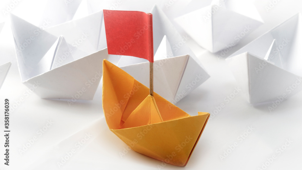 Red flag Yellow Origami Paper boat (ship )leading among white. White background. Success and Leadership concept Red flag Yellow Origami Paper boat (ship )leading among white. White background. Success and Leadership concept