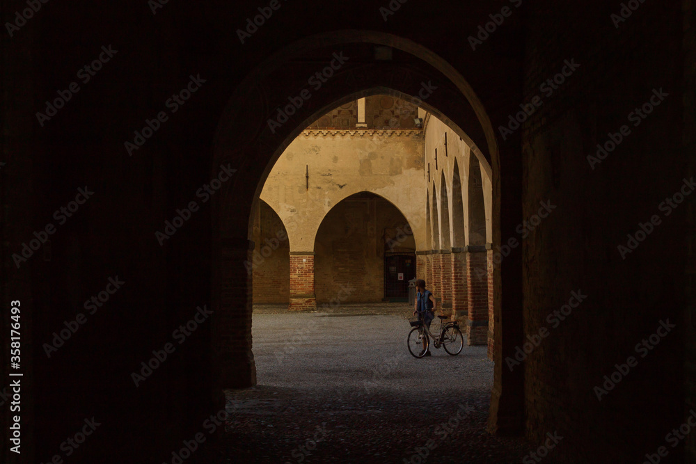 A young man with a bicycle in Visconteo Castle in Pandino, Lombardy, Italy