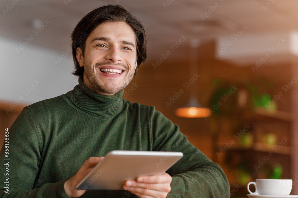 Smiling male blogger working online at cafe, using digital tablet Smiling male blogger working online at cafe, using digital tablet