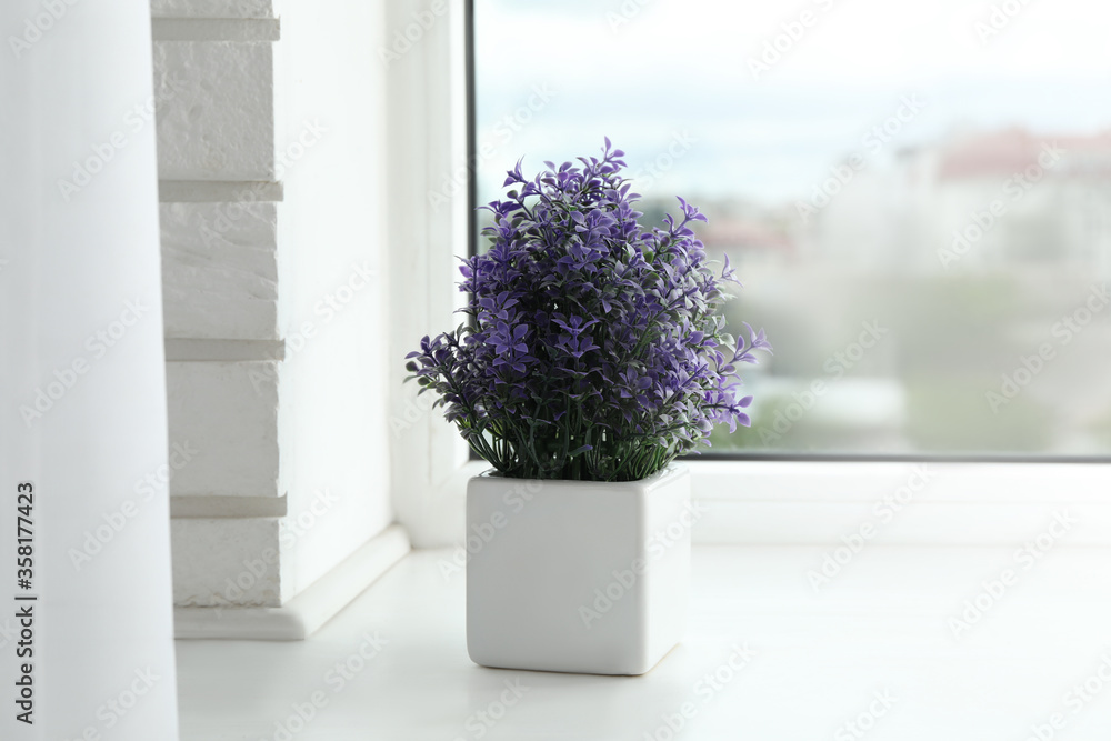 Beautiful artificial plant in flower pot on window sill Beautiful artificial plant in flower pot on window sill