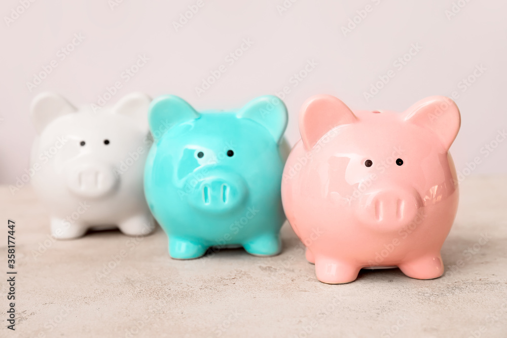 Piggy banks on table against light background Piggy banks on table against light background