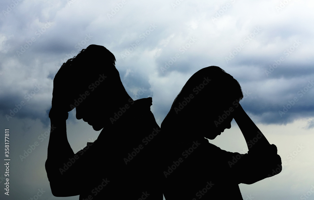 Silhouettes of arguing couple against sky with heavy rainy clouds. Relationship problems