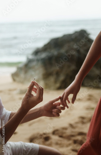 The guy gives the girl a engagement ring on the ocean beach