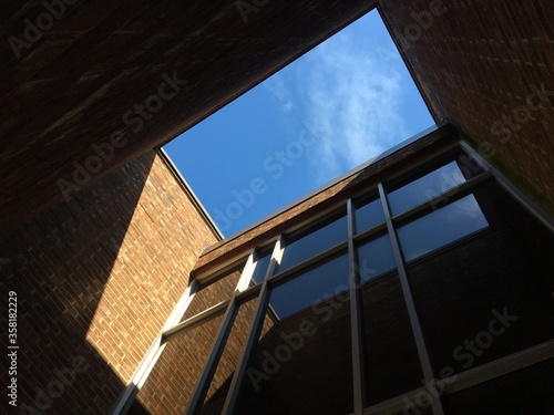 the exterior of a modern office building with black windows and sunshine coming in creating shadows and reflections with clear blue sky 