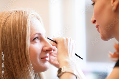 Beautician draws model eyebrows on face model