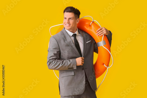 Φωτογραφία Young businessman with lifebuoy on color background