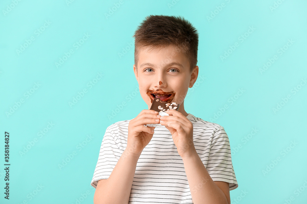Cute little boy eating chocolate on color background Cute little boy eating chocolate on color background