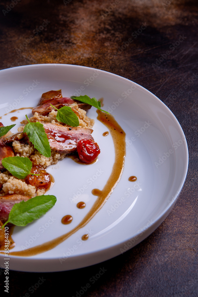 A quinoa, teriyaki sauce and confit tomatoes on a white plate against a dark background. Master class in the kitchen. The process of cooking. Dish from the restaurant menu. European cuisine. Close-up A quinoa, teriyaki sauce and confit tomatoes on a white plate against a dark background. Master class in the kitchen. The process of cooking. Dish from the restaurant menu. European cuisine. Close-up