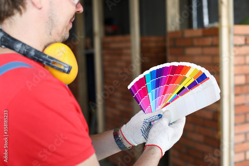 Builder holding palette standing front brickwork