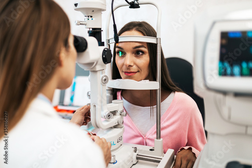 Female optometrist checking patient s vision at eye clinic. Healthcare and medical concept.