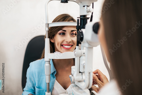 Fototapeta Naklejka Na Ścianę i Meble -  Female optometrist checking patient's vision at eye clinic. Healthcare and medical concept.