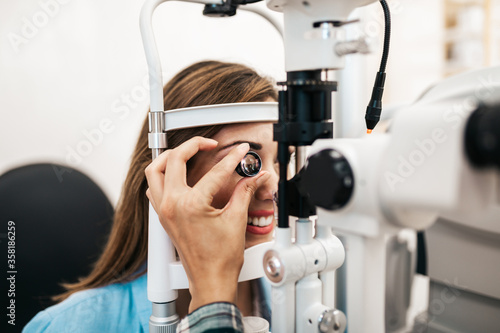 Female optometrist checking patient's vision at eye clinic. Healthcare and medical concept.