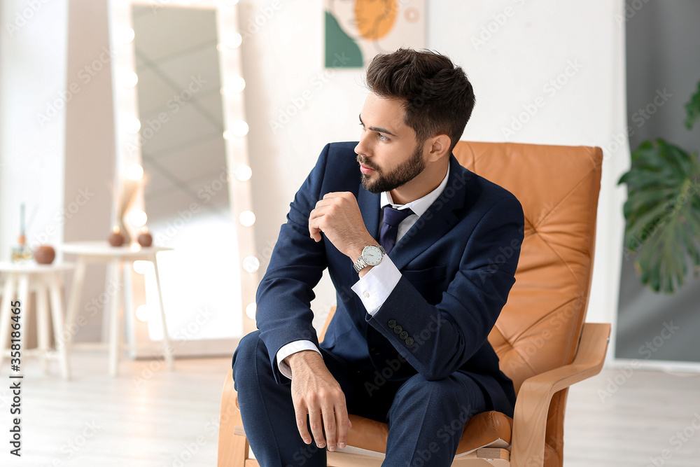 Stylish young man sitting in armchair indoors Stylish young man sitting in armchair indoors