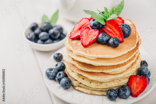 Classic american pancakes with fresh berry on white wood background. Summer homemade breakfast.
