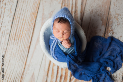 first photo session. portrait of a newborn baby. a child in a blue hat in a basket. chair posing