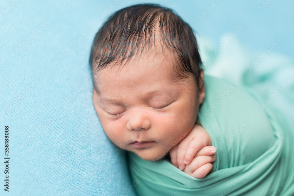 first photo session. portrait of a newborn baby. the child is lying on a blue background first photo session. portrait of a newborn baby. the child is lying on a blue background