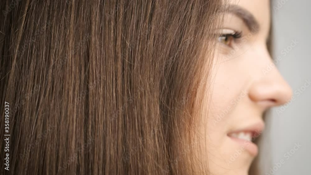 Beautiful woman with black eyes stands in front of a mirror in the bathroom and combs her long hair Beautiful woman with black eyes stands in front of a mirror in the bathroom and combs her long hair