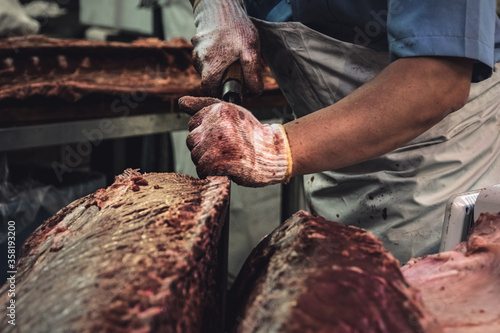 Fotografie Fishmonger wearing blooded gloves filleting giant tuna in the Tsukiji Outer Market area, Tokyo, Japan
