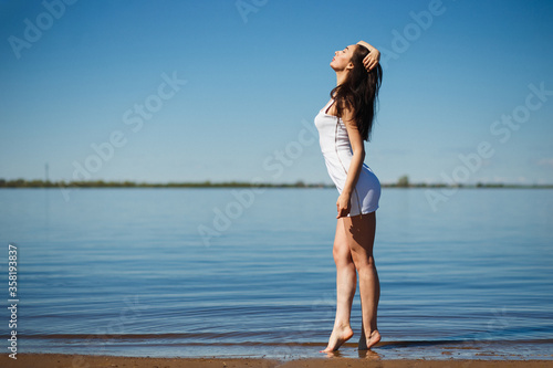 Young sexy lady in the white dress standing in the warm water. © Northern life