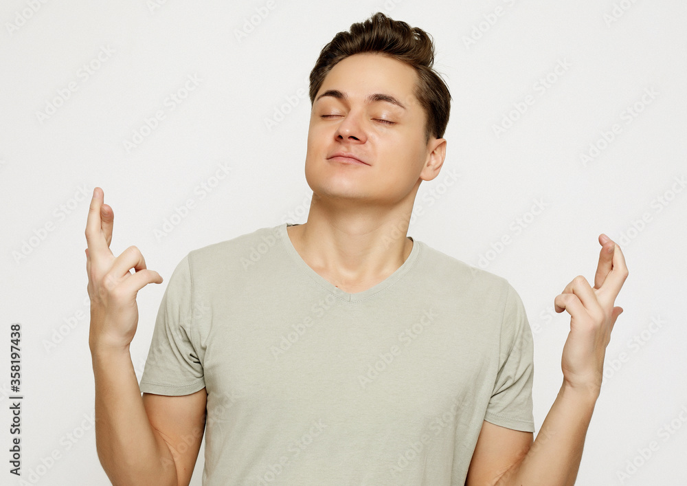 Portrait of charming caucasian man raising hands with crossed fingers and smiling Portrait of charming caucasian man raising hands with crossed fingers and smiling