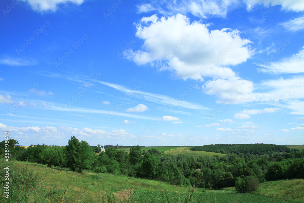 Beautiful summer landscape of nature countryside. Green vegetation of grass and trees with hills. Stock photo for design