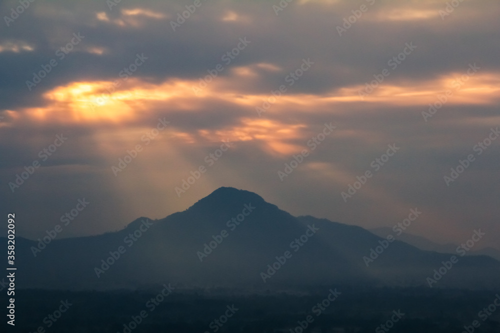sunset over the mountains with sunlight through clouds 