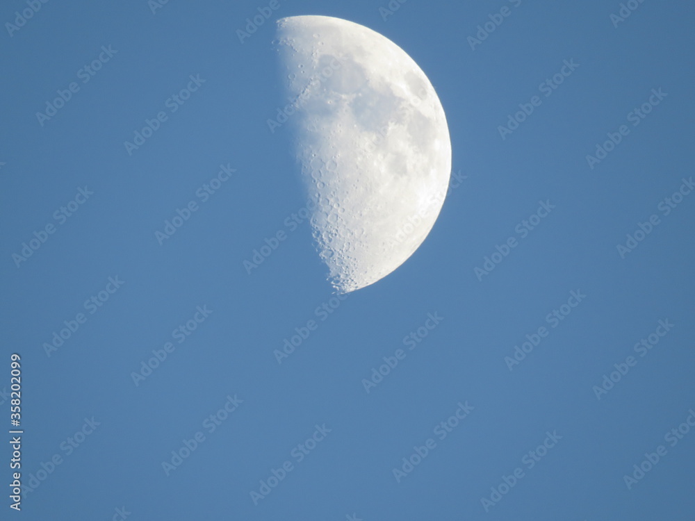 Moon in the blue sky. Large white moon on a clear blue sky without clouds in the daytime, sunny day time. Moon in the blue sky. Large white moon on a clear blue sky without clouds in the daytime, sunny day time.
