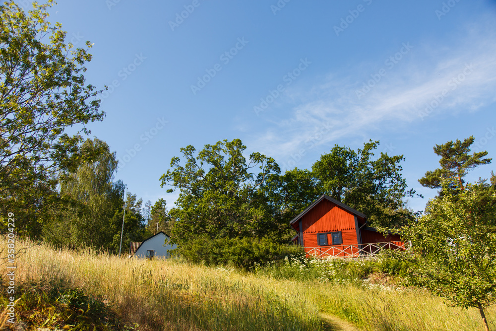 Fototapeta premium Red summer garden cottage in Sweeden. Traditional Sweden wooden old house. Life on the one of Sweeden islands