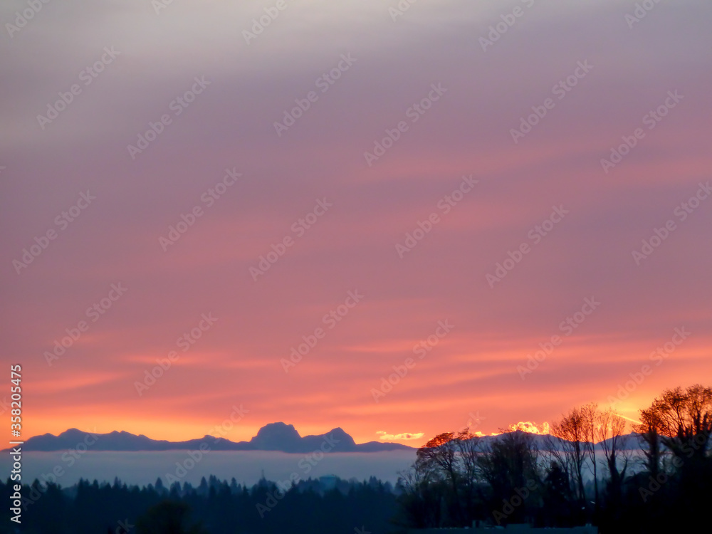 Sunrise over Cascade Mountain Range in Washington State with violet, orange, and yellow sky.