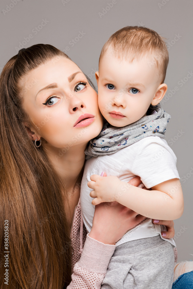 Φωτογραφία Beautiful young mother and little sweet son embracing, woman gesturing and pointing at camera by finger