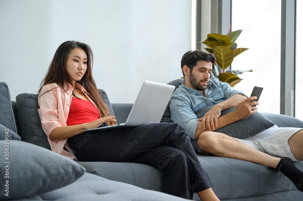 Happy and relax lifestyle of young couple lover wearing casual dress together working on sofa with laptop notebook computer in living room at home. Happy and relax lifestyle of young couple lover wearing casual dress together working on sofa with laptop notebook computer in living room at home.