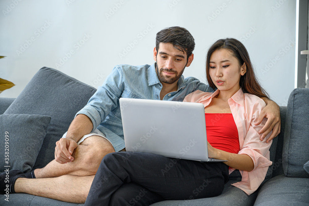 Happy and relax lifestyle of young couple lover wearing casual dress together working on sofa with laptop notebook computer in living room at home. Happy and relax lifestyle of young couple lover wearing casual dress together working on sofa with laptop notebook computer in living room at home.