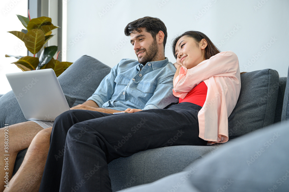 Happy and relax lifestyle of young couple lover wearing casual dress together working on sofa with laptop notebook computer in living room at home. Happy and relax lifestyle of young couple lover wearing casual dress together working on sofa with laptop notebook computer in living room at home.