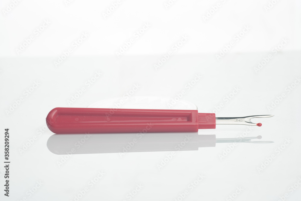 seam ripper isolated over white reflective background seam ripper isolated over white reflective background