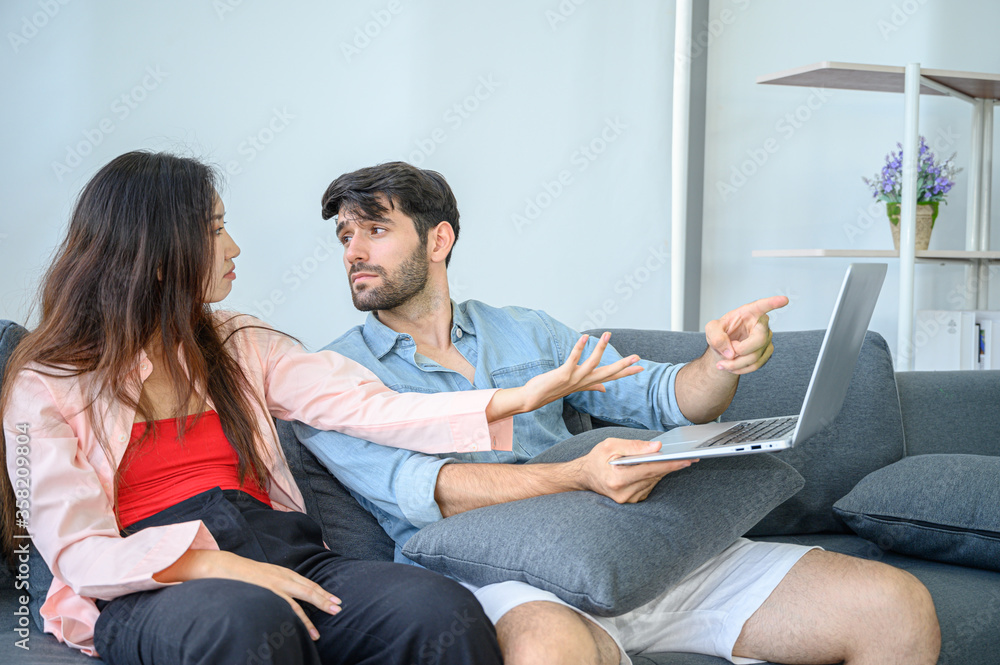 Unhappy of young couple lover wearing casual dress together working on sofa with laptop notebook computer in living room at home. Unhappy of young couple lover wearing casual dress together working on sofa with laptop notebook computer in living room at home.