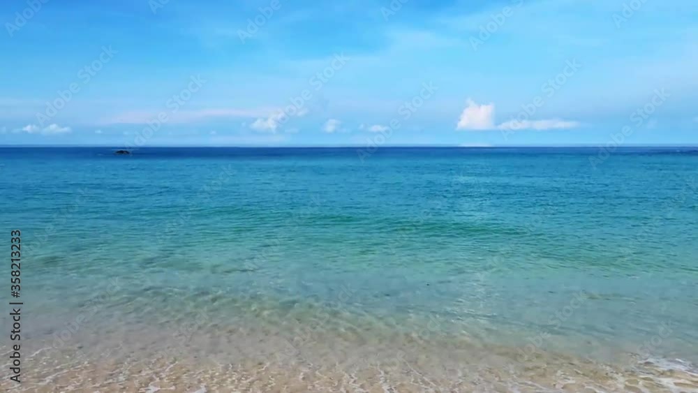Tropical summer sand beach view with crystal clear blue or green water surface & calm soft waves reaching sandy seashore & coastline on beautiful sunny clear sky & white clouds background, Andaman Sea Tropical summer sand beach view with crystal clear blue or green water surface & calm soft waves reaching sandy seashore & coastline on beautiful sunny clear sky & white clouds background, Andaman Sea