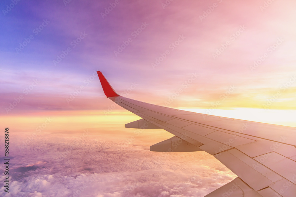 Obraz premium Aircraft left wing on the sky above the clouds at Sunrise dawn.