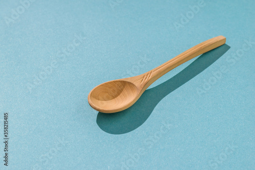 Light wooden spoon on a blue background in hard light.