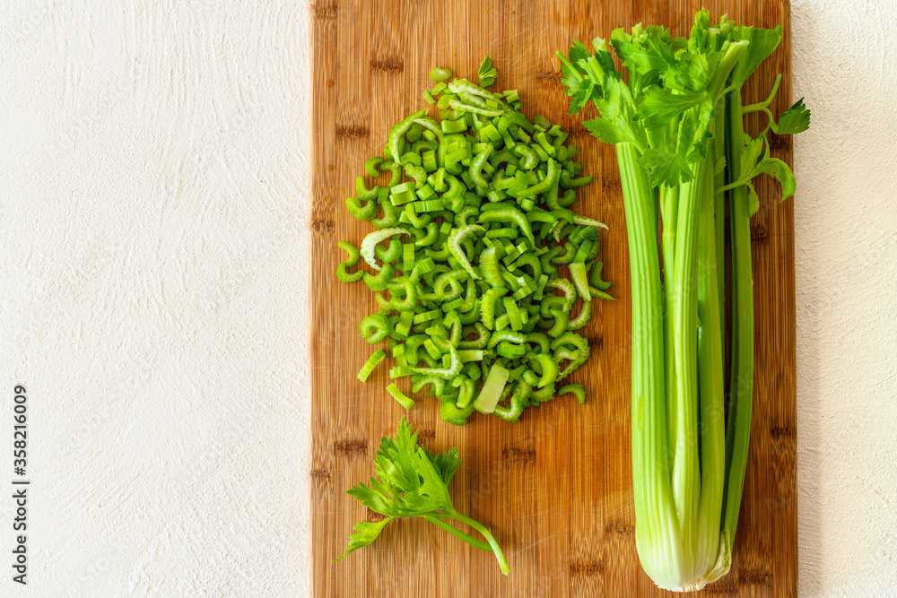 Sliced fresh celery close up on wooden cutting board on white background with copy space Sliced fresh celery close up on wooden cutting board on white background with copy space