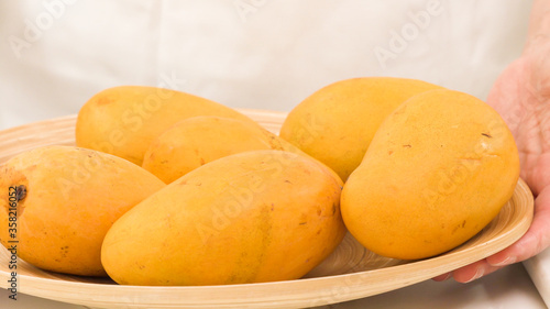 Yellow mangoes close up. Fresh ripe organic fruits on wooden plate