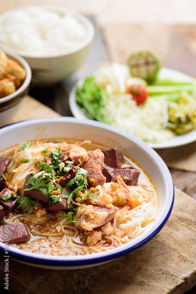 Northern Thai food (Kanom Jeen Nam Ngeaw), Rice noodles spicy soup with pork and pork blood in bowl eating with fresh vegetables and pork rind Northern Thai food (Kanom Jeen Nam Ngeaw), Rice noodles spicy soup with pork and pork blood in bowl eating with fresh vegetables and pork rind