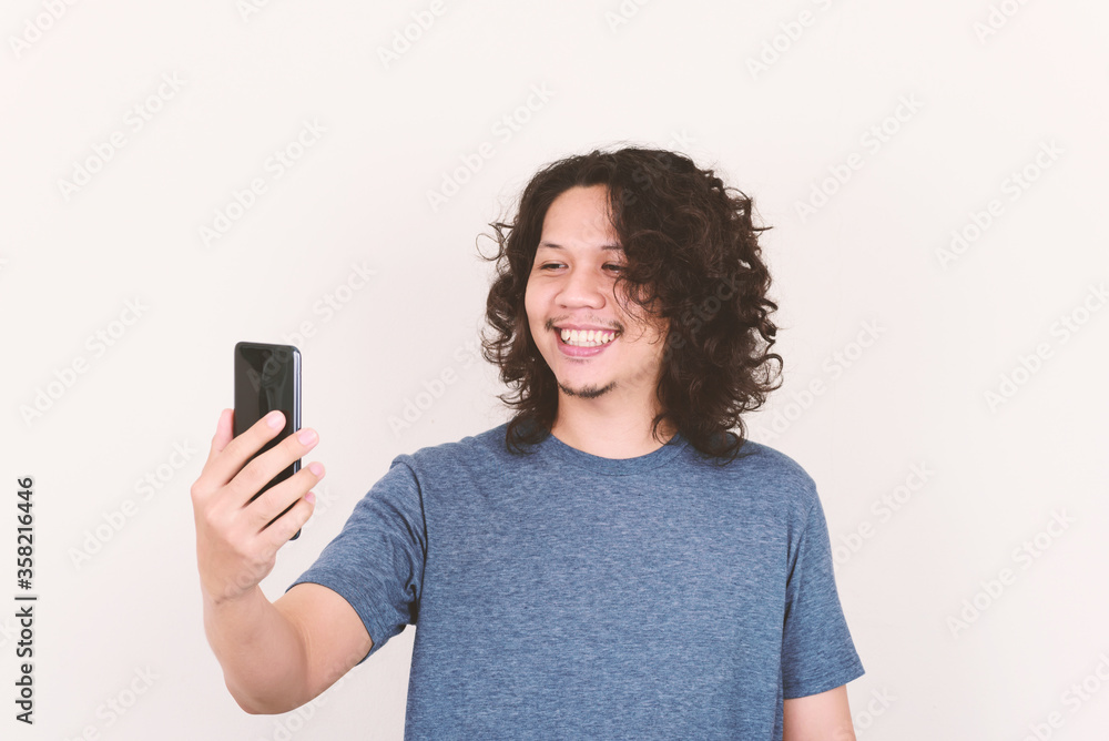 Portrait of Asian man smiling and holding mobile phone for selfie, video call or playing social media Portrait of Asian man smiling and holding mobile phone for selfie, video call or playing social media