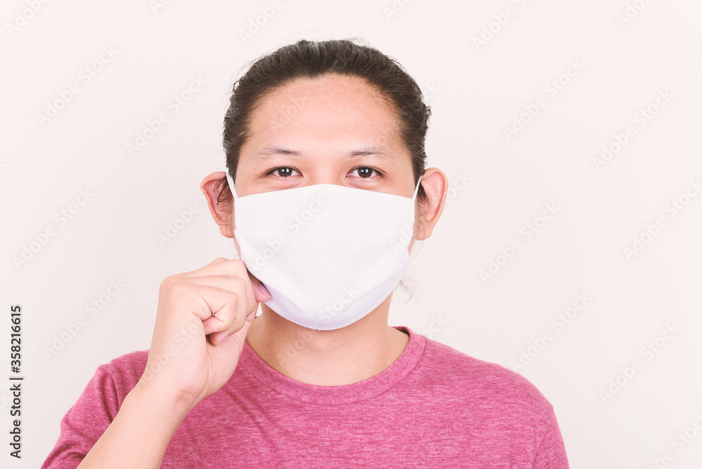 Portrait of Asian man wearing white fabric mask to protection corona virus outbreak and pollution on white concrete wall Portrait of Asian man wearing white fabric mask to protection corona virus outbreak and pollution on white concrete wall