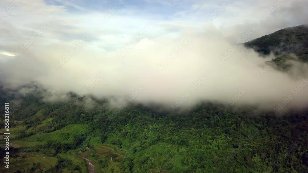 Aerial view flying thru the morning rain cloud covered tropical rain forest mountain landscape during the rainy season on the Doi Phuka Mountain reserved national park the northern Thailand Aerial view flying thru the morning rain cloud covered tropical rain forest mountain landscape during the rainy season on the Doi Phuka Mountain reserved national park the northern Thailand