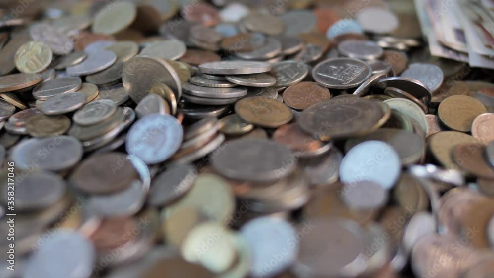 Close up on coins falling on pile of money, selective focus Close up on coins falling on pile of money, selective focus