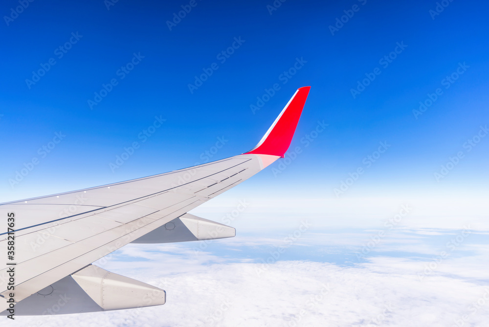 Fototapeta premium View from window of aircraft right wing on the blue sky above the clouds.