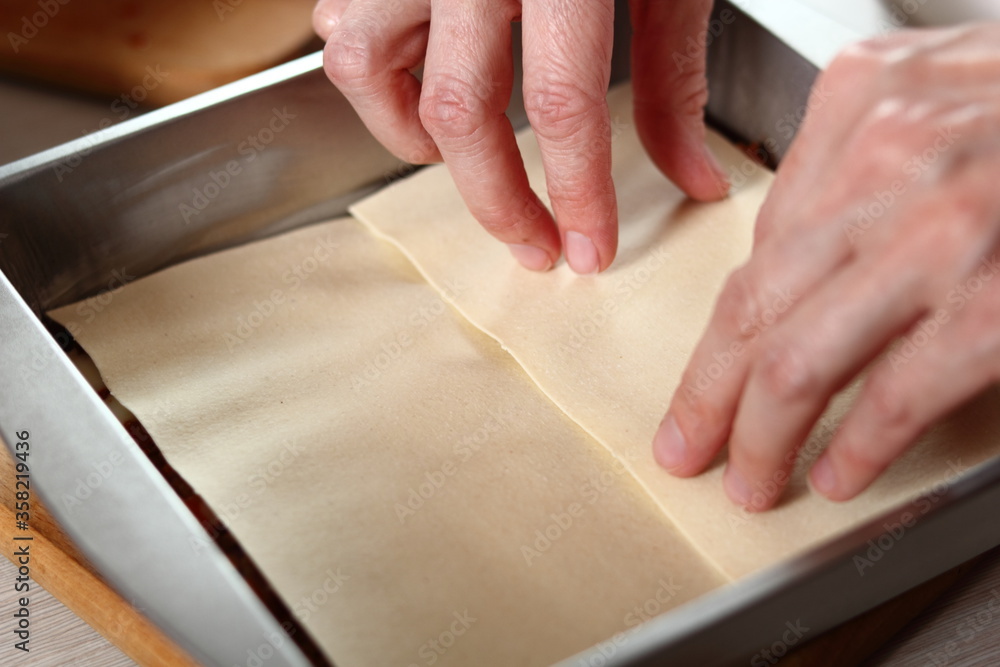 Obraz premium Place pasta sheets on meat layer. Making Lasagna Bolognese Series.
